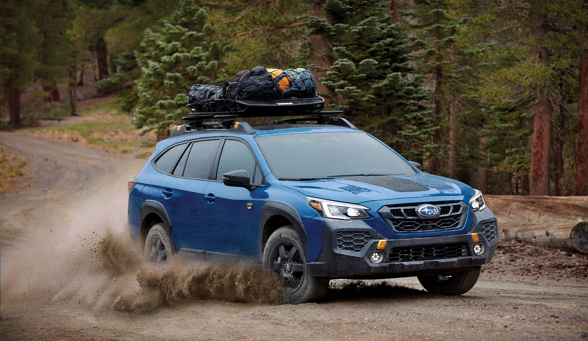 Subaru Outback Wilderness 2025 Outback Wilderness 2025 roulant sur une route en gravier avec un panier à bagages sur le toit.